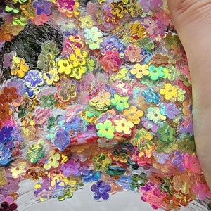 May include: Clear slime with iridescent flower-shaped glitter. The slime is thick and gooey, and the glitter is scattered throughout.