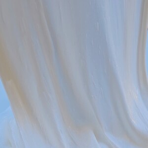 May include: Close-up of white slime with a smooth, glossy texture. The slime is draped over itself, creating folds and ripples.