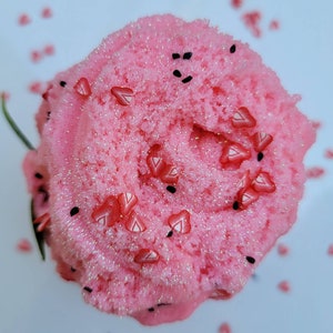 Peut inclure: Slime rose avec des paillettes et des p&eacute;pites en forme de c&oelig;ur rouges. Le slime est dans un r&eacute;cipient transparent et repose sur une surface blanche.