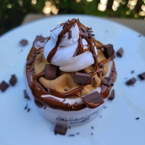 以下が含まれることがあります： チョコレートチップワッフルカップにホイップクリーム、チョコレートソース、チョコレートチップがトッピングされています。カップには「チョコレートチップワッフル」とラベルが貼られています。