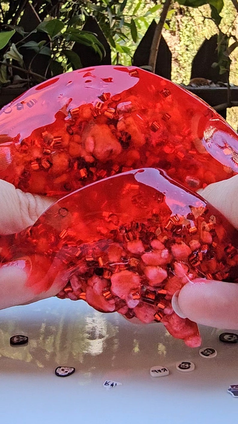 May include: Red slime with red and gold glitter inside. The slime is being held in two hands.