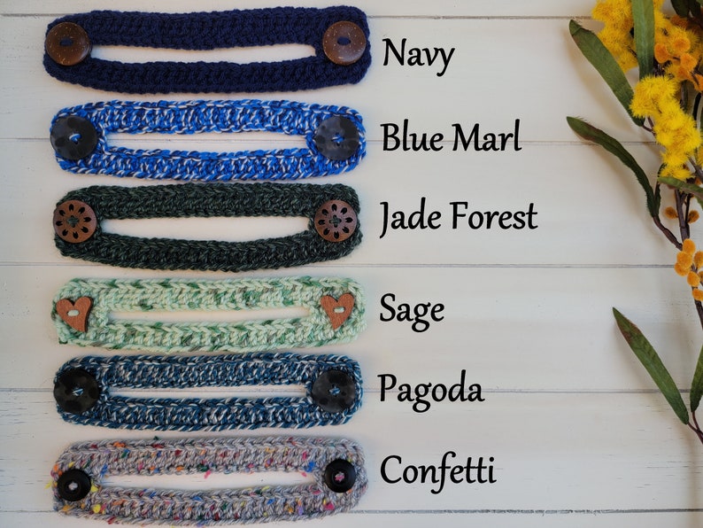 Op de afbeelding: Zes gebreide maskerverlengers in verschillende kleuren en patronen, waaronder marineblauw, blauw marmer, jadebos, salie, pagode en confetti. Elke verlenging heeft twee knopen aan de uiteinden.