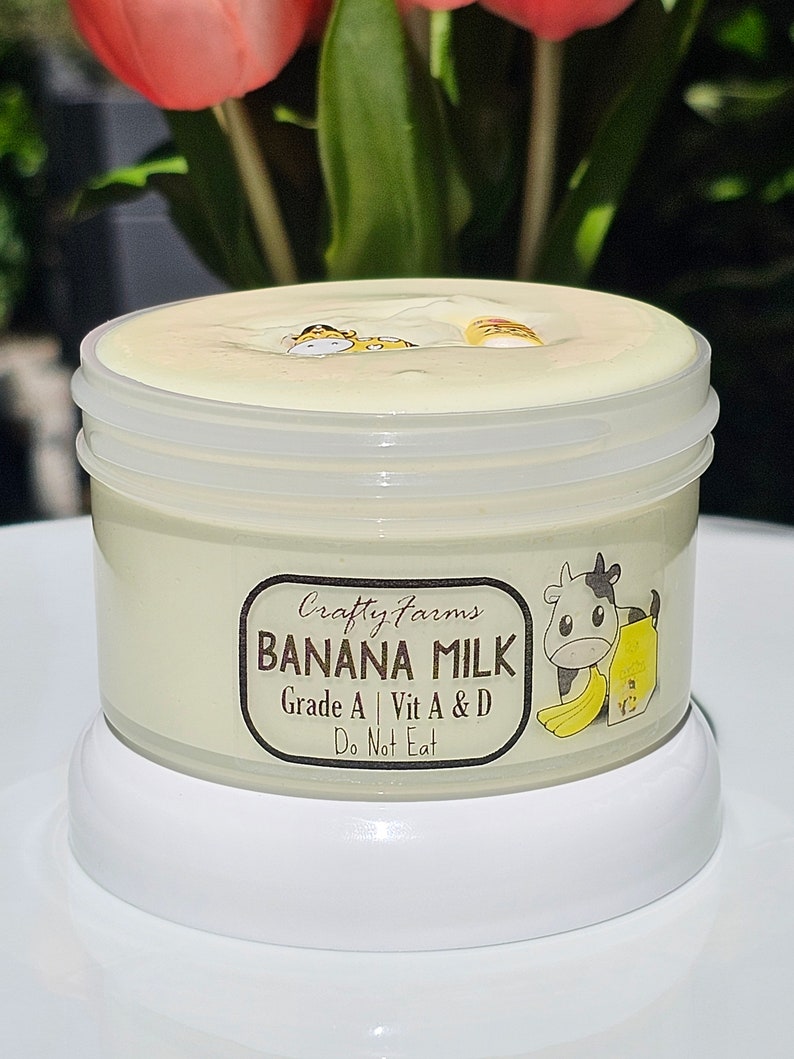 May include: A white jar of banana milk slime with a cartoon cow and banana on the label. The label reads "Crafty Farms Banana Milk Grade A | Vit A & D Do Not Eat".