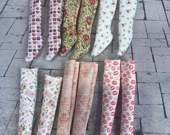 May include: A collection of knee-high socks with various patterns. Designs include chocolate hearts, floral hearts, white socks with red hearts, socks with the word "Love", pink floral patterns, and socks covered in red lip prints.