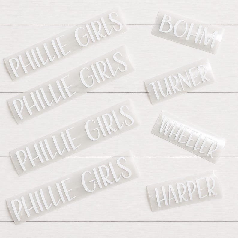 May include: A collection of white vinyl adhesive decals featuring custom text. Four decals display the phrase PHILLIE GIRLS, while four individual decals feature the names BOHM, TURNER, WHEELER, and HARPER in a clean, sans-serif font style.