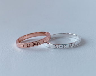 May include: Two simple wedding bands, one silver and one rose gold, with the inscription "HK-16.10.19" and "MG-16.10.19" on them.