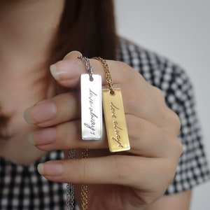 May include: Two silver and gold necklaces with matching rectangular pendants that say "love always" in cursive.