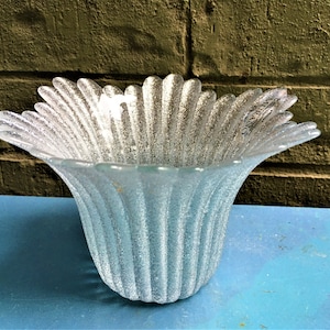 May include: A clear glass vase with a textured, rippled surface. The vase has a wide, flared opening and a narrow base. The vase is made by the company "Murano".