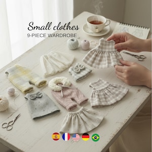 Może przedstawiać: Kolekcja dziewięciu miniaturowych ubranek dla lalek, w tym sukienki, spodnie i spódnice, w różnych pastelowych kolorach. Wyświetlany jest tekst "Small clothes 9-PIECE WARDROBE". Widoczna jest również filiżanka herbaty i akcesoria do szycia.