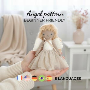 Pode incluir: Uma boneca de anjo feita à mão com uma saia de tule bege, asas creme e cabelo de fio loiro. O texto "Angel pattern BEGINNER FRIENDLY" é exibido acima da boneca. A imagem também mostra bandeiras representando 5 idiomas.