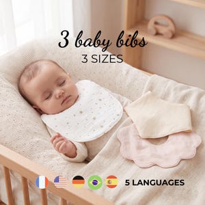 Puede incluir: Tres baberos para bebé en tres tamaños. Un babero blanco con estampado de estrellas doradas lo lleva un bebé dormido. Un babero triangular color crema y un babero rosa claro con bordes festoneados están colocados al lado. Texto: 3 baby bibs, 3 SIZES, 5 LANGUAGES.
