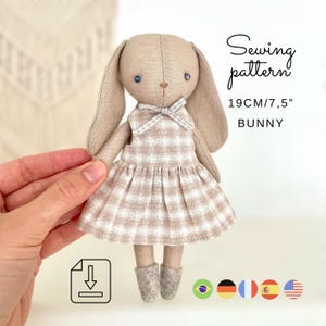 May include: A fabric bunny doll with a plaid dress and boots. The doll is approximately 19 cm tall. The image includes the text "Sewing pattern" and "Bunny".