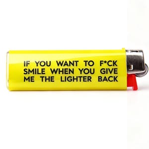 Pu&ograve; includere: Un accendino giallo con testo nero che recita "IF YOU WANT TO F*CK SMILE WHEN YOU GIVE ME THE LIGHTER BACK." L'accendino ha un pulsante di accensione rosso e una parte superiore in metallo argentato. L'accendino &egrave; su sfondo bianco.