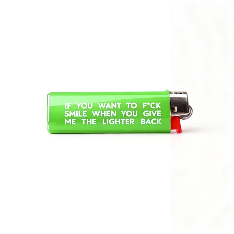 Puede incluir: Un encendedor verde con el texto "IF YOU WANT TO F*CK SMILE WHEN YOU GIVE ME THE LIGHTER BACK" en blanco. El encendedor tiene un bot&oacute;n de encendido rojo y una parte superior de metal plateado. El fondo es blanco.