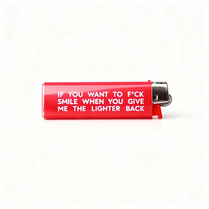 Pu&ograve; includere: Un accendino rosso con la scritta "IF YOU WANT TO F*CK SMILE WHEN YOU GIVE ME THE LIGHTER BACK" in bianco. L'accendino ha una parte superiore in metallo argentato e un corpo in plastica rossa.