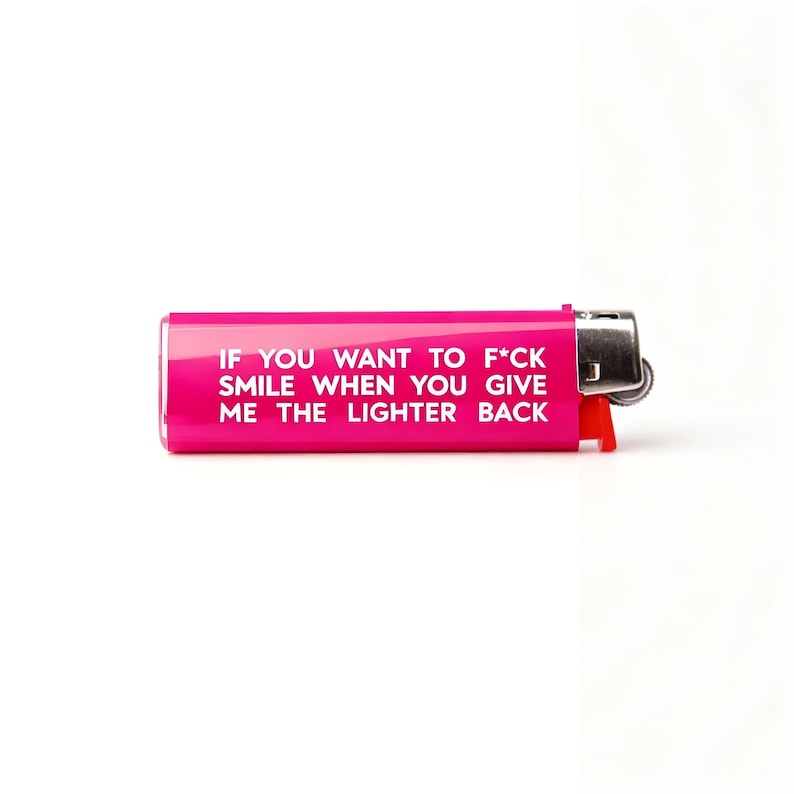 Puede incluir: Un encendedor rosa brillante con el texto "IF YOU WANT TO F*CK SMILE WHEN YOU GIVE ME THE LIGHTER BACK" en blanco. Tiene una parte superior de metal plateado y un interruptor de encendido rojo.