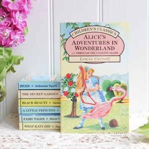 May include: A stack of classic children's books with colorful covers, including "Heidi", "The Secret Garden", "Black Beauty", "A Little Princess", "Fairy Tales", and "What Katy Did".  The top book is "Alice's Adventures in Wonderland and Through the Looking Glass" by Lewis Carroll, featuring an illustration of Alice playing croquet with a flamingo.