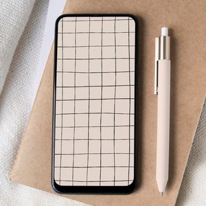 May include: A black smartphone with a grid pattern on the screen, a beige pen, and a cup of coffee on a white surface.