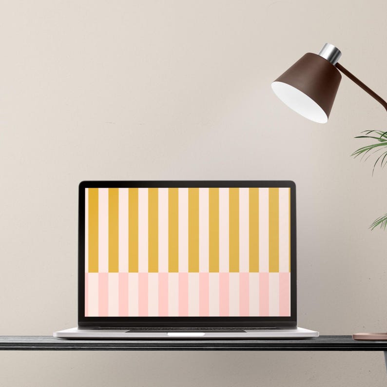 May include: A laptop displays a colorful striped pattern in yellow, pink, and white. The laptop sits on a black desk, with a brown desk lamp and a plant visible in the background. The screen's design is a modern, minimalist aesthetic.