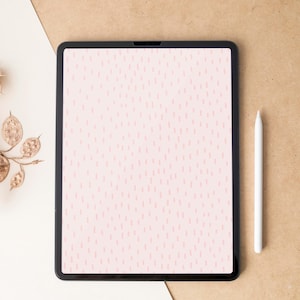 May include: A black tablet displaying a pink dotted pattern, accompanied by a white stylus. The tablet rests on a tan surface with a white and tan backdrop. A gold decorative branch is in the upper left corner.