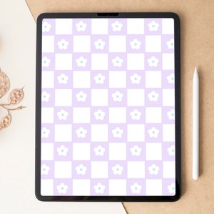 Puede incluir: Una tableta digital muestra un patrón de tablero de ajedrez con cuadrados lavanda y blancos. Cada cuadrado lavanda presenta una flor blanca con un centro azul claro. Un lápiz óptico blanco descansa junto a la tableta sobre una superficie marrón.