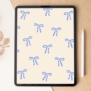 Puede incluir: Una tableta digital que muestra un patrón de papel tapiz de lazos azules sobre un fondo crema.