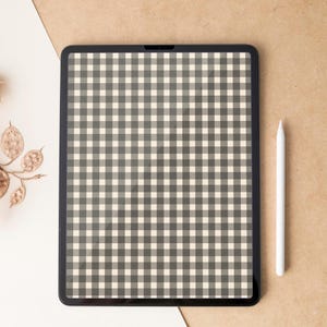 Puede incluir: Una tableta digital con bisel negro muestra un patrón de cuadros grises y crema. Un lápiz óptico blanco descansa junto a la tableta sobre una superficie beige. La escena se desarrolla sobre un fondo blanco y beige, lo que sugiere un tema de diseño o arte.