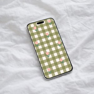 Puede incluir: Un smartphone con una funda transparente muestra un patrón de cuadros verdes y blancos con ilustraciones de tulipanes rosas. El teléfono está colocado sobre una superficie blanca texturizada, mostrando el diseño floral de la pantalla.