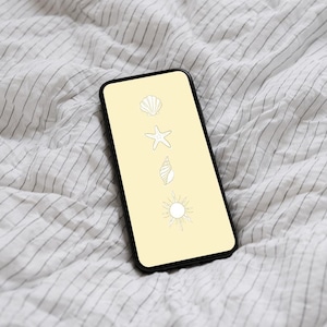 以下が含まれることがあります： 黒いスマートフォンは、貝殻、ヒトデ、渦巻き貝、太陽の白い線画が描かれた淡い黄色の画面を表示しています。 電話は白と灰色のストライプの生地の上にあります。