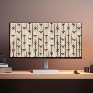 May include: A computer monitor displaying a repeating pattern of black bows on vertical lines against a beige background. The monitor is on a wooden desk with a mouse, pens, and books.