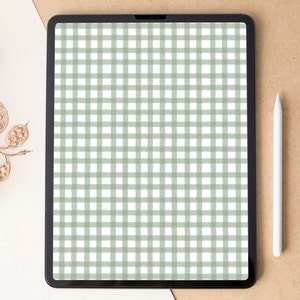 Puede incluir: Una tableta con un patrón de cuadros verdes y blancos en la pantalla. La tableta está sobre una superficie blanca con una superficie marrón a la derecha. Un lápiz blanco está sobre la superficie marrón.