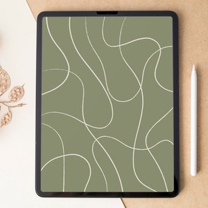 May include: A digital tablet displays an abstract design of white, curving lines on a muted green background. A white stylus rests beside the tablet on a brown surface. Dried, decorative seed pods are on a white surface.
