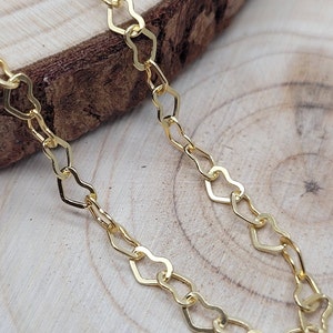 May include: A gold heart-shaped chain necklace. The chain is made of small, interconnected heart-shaped links.