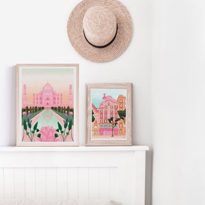 May include: Two framed illustrations of buildings. The first illustration is of the Taj Mahal in pink and white with a reflecting pool in the foreground. The second illustration is of a pink building with a green tree in front of it.