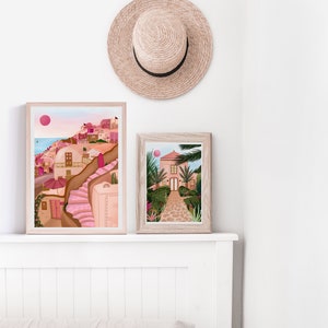 May include: Two framed illustrations of pink buildings with a white background. The top illustration shows a pink building with a pink staircase and a pink umbrella. The bottom illustration shows a pink building with a green garden and a stone path.