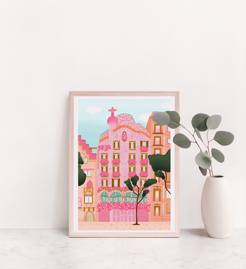 May include: A framed illustration of a pink building with a whimsical design, surrounded by trees and flowers. The building has a unique, curved roof and multiple windows. The illustration is set against a blue sky with white clouds.