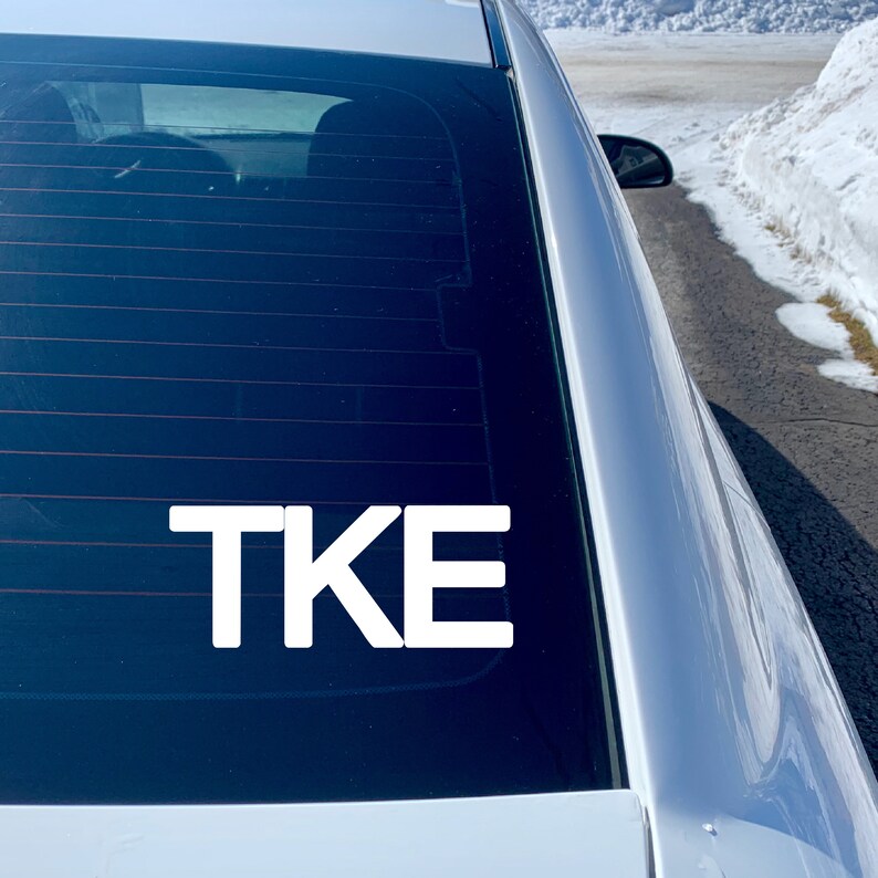 May include: White vinyl decal with the letters "TKE" on a car window.
