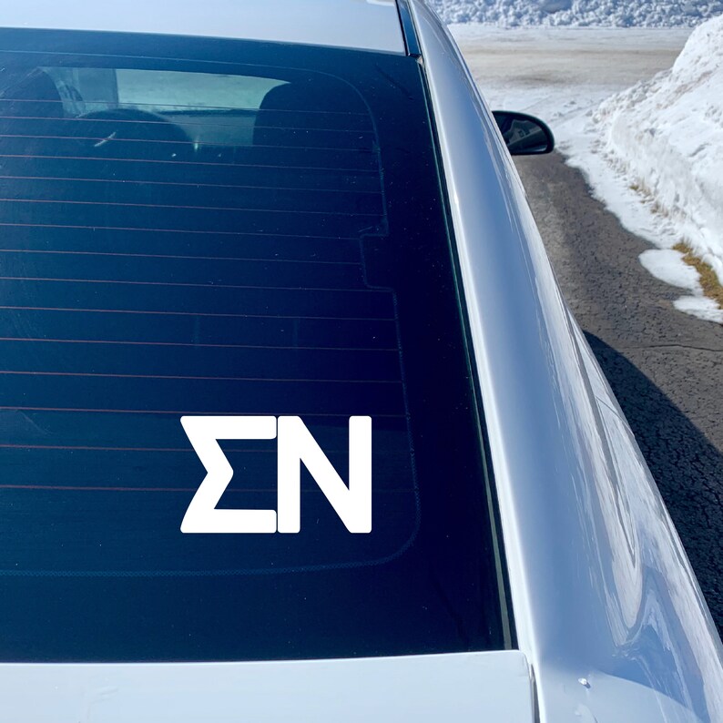 May include: A white vinyl decal with the letters "&Sigma;N" on a black car window.