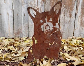 May include: A rusty metal silhouette of a corgi dog, standing on a bed of brown leaves.