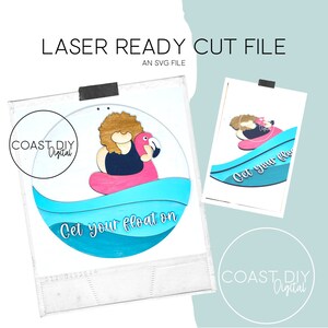 May include: A round wooden sign with a blue, pink, and white wave design. The sign features a cartoon person riding a pink flamingo float and the text "Get your float on".