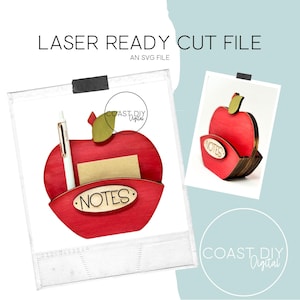 May include: Red apple-shaped wooden desk organizer with a slot for notes and a pen holder. The organizer has the word "NOTES" written on it.