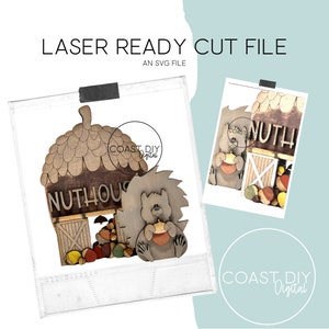 May include: Laser cut file for a wooden nut house with a squirrel holding a nut. The house is shaped like an acorn and has the text "Nuthouse" on the front. The file is an SVG file.