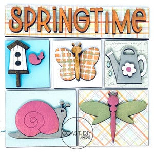 K&ouml;nnte beinhalten: Ein Holzschild mit dem Wort "SPRINGTIME" in orangefarbenen Buchstaben. Das Schild ist mit verschiedenen Fr&uuml;hlingsmotiven aus Holz verziert, darunter ein Vogelhaus, ein Schmetterling, eine Gie&szlig;kanne, eine Schnecke und eine Libelle. Der Hintergrund zeigt Pastellfarben und Karomuster.