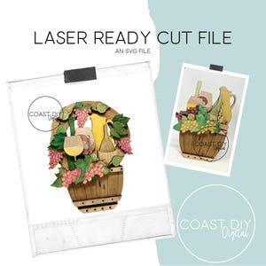 May include: Wooden laser-cut file featuring a wine-themed design. The design includes a wine barrel, grapes, wine glasses, and bottles. The text "LASER READY CUT FILE" and "AN SVG FILE" are visible. The image is in a square format.