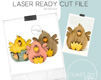 May include: Laser cut file for a set of three wooden chicks. The chicks are in different colors: yellow, pink, and brown. The yellow chick is in an egg, the pink chick is standing, and the brown chick is standing with its wings out.