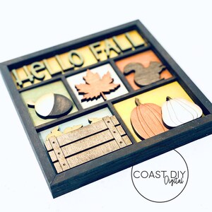 May include: A wooden framed wall decor with the words "Hello Fall" in a multi-colored font. The frame is divided into nine sections, each containing a different fall-themed image, including a leaf, an acorn, a squirrel, a pumpkin, and a crate.