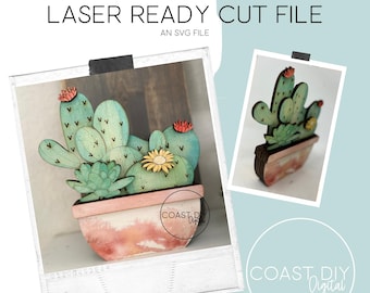 Puede incluir: Un diseño de archivo de corte SVG cortado por láser de una planta de cactus en maceta con una maceta rosa. El cactus es verde con acentos marrones y tiene una flor amarilla. El diseño es perfecto para proyectos de manualidades.