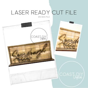 May include: A laser cut file for a wooden sign that says "Sourdough" in a script font with a small branch of leaves. The sign is on a plaid background.