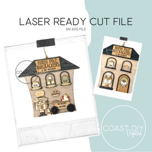 Op de afbeelding: Een lasergesneden bestand voor een houten ornament in de vorm van een huis met de tekst "North Pole Nutcrackers & Toy Roastery". Het ornament toont een notenkraker die een karretje met de tekst "Hot Cocoa Dreams" vasthoudt.