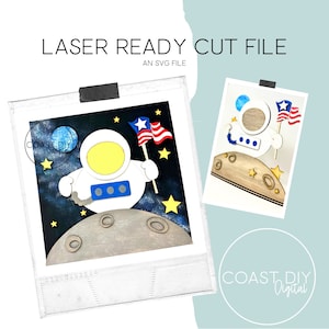 Könnte beinhalten: Laserschnittdatei für einen geschichteten Astronauten, der eine amerikanische Flagge auf dem Mond hält. Der Astronaut ist weiß mit einem gelben Helm und blauen Details. Der Mond ist braun mit Kratern. Der Hintergrund ist dunkelblau mit weißen Sternen.